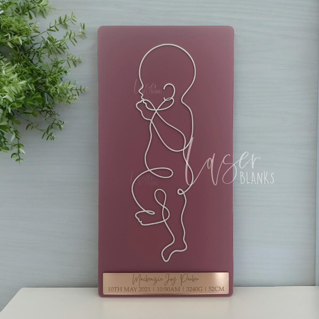 Layered 1:1 baby line art cut from acrylic showing raised baby figure and engraved plaque mounted on backboard