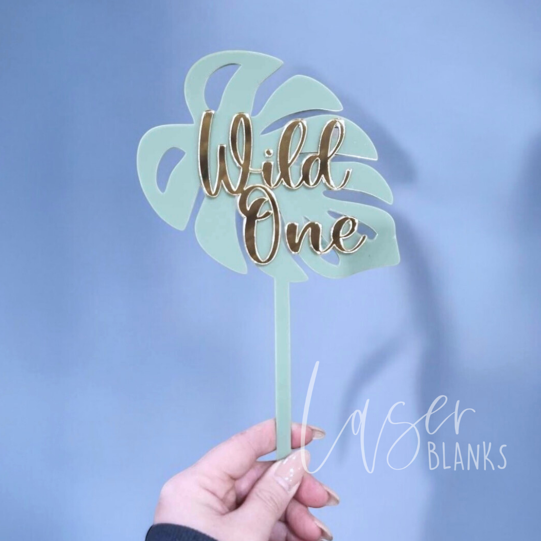 Wild One cake topper in gold script on eucalyptus leaf acrylic base – perfect for first birthday cakes